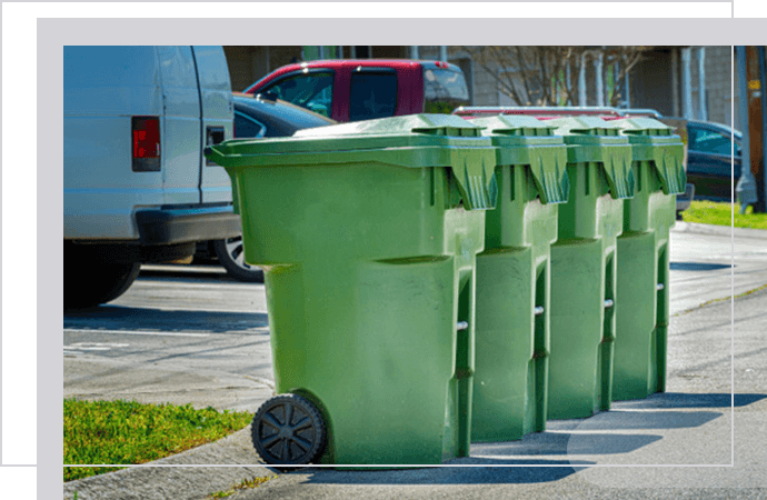 Row of green waste bins lined up on a residential street.