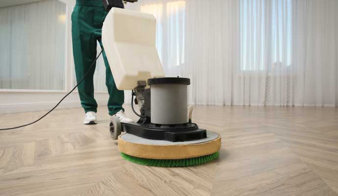 Person cleaning wooden floor with equipment